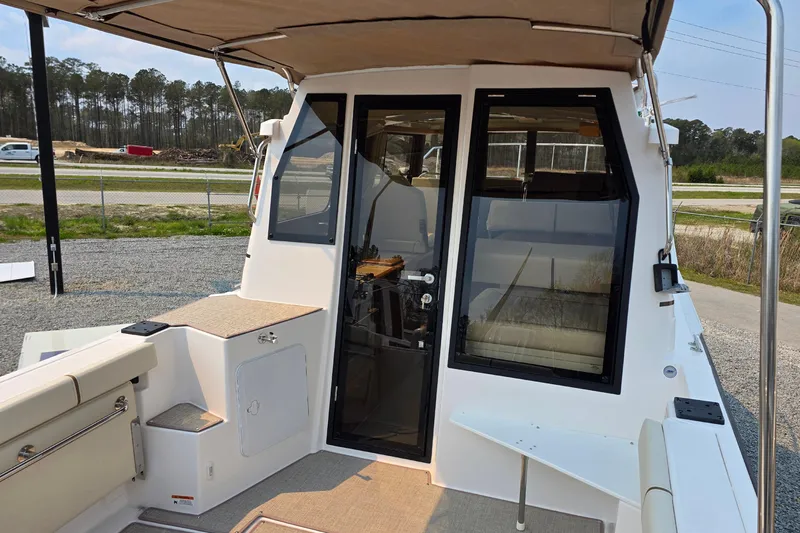 Slide: The Image of 2026 Ranger Tugs R-27 boat deck with seating and canopy, parked outdoors. - 4