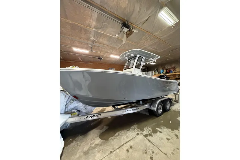 The Image of 2026 Sportsman Open 232 Center Console boat on trailer in a garage. - 0