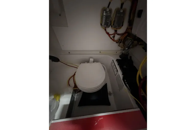 Slide: The Image of Interior of 2026 Sportsman Open 232 Center Console boat, featuring a compact marine toilet. - 14