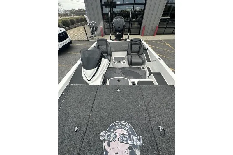 Slide: The Image of 2021 Caymas CX 19 boat interior with seating and motor, parked outside a building. - 9