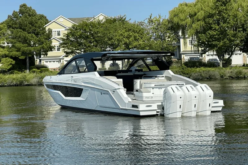Slide: The Image of 2024 Cruisers Yachts 50 GLS luxury boat on calm water, surrounded by greenery. - 10