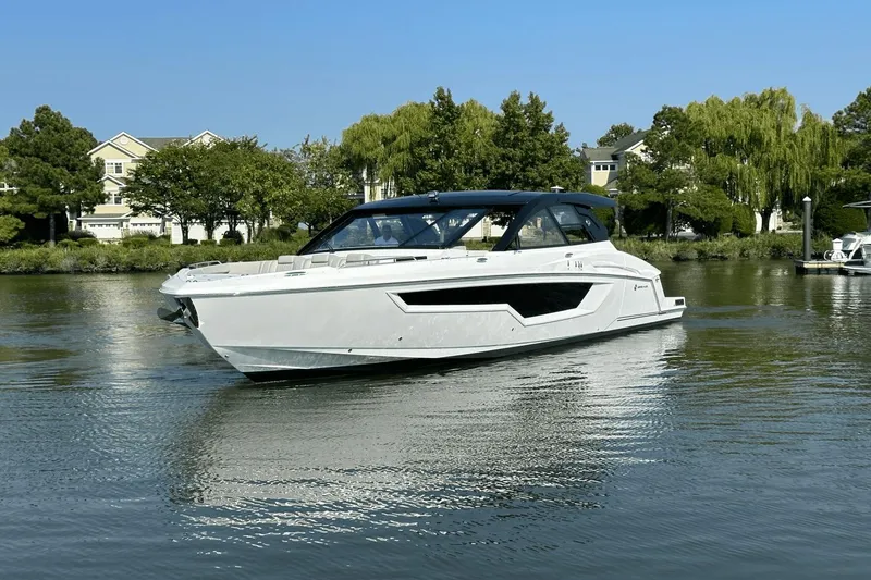 Slide: The Image of 2024 Cruisers Yachts 50 GLS luxury boat on calm water, surrounded by lush greenery. - 4