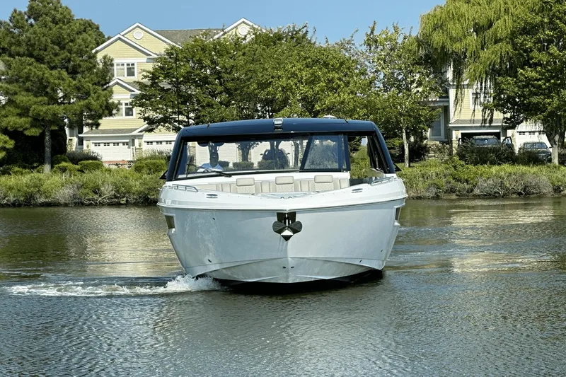 Slide: The Image of 2024 Cruisers Yachts 50 GLS on a serene waterway, surrounded by lush greenery. - 7