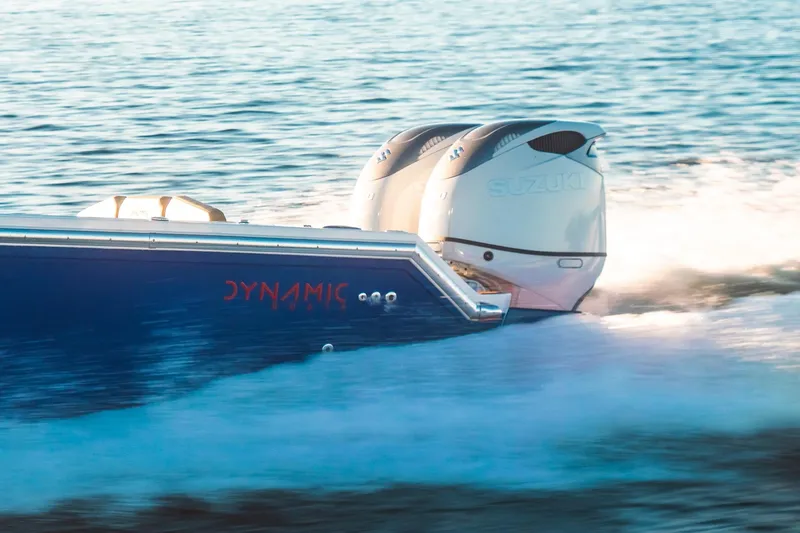 Slide: The Image of 2023 Dynamic D-305V boat with dual Suzuki outboard engines cruising on water. - 10