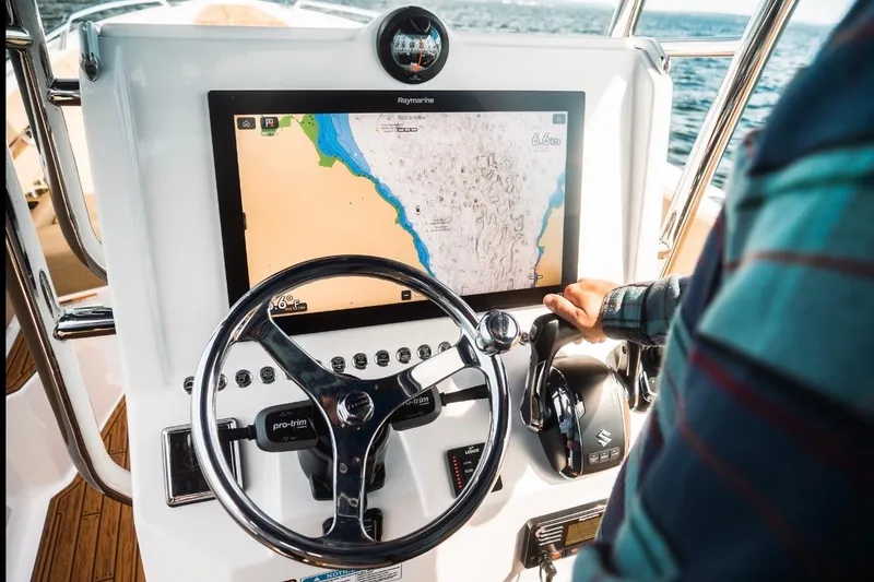 Slide: The Image of Boat dashboard with navigation screen, steering wheel, and controls on a Dynamic D-305V, 2023 model. - 12
