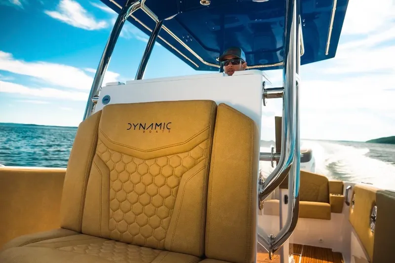 Slide: The Image of Dynamic D-305V boat interior with tan seating, cruising on open water, 2023 model. - 16