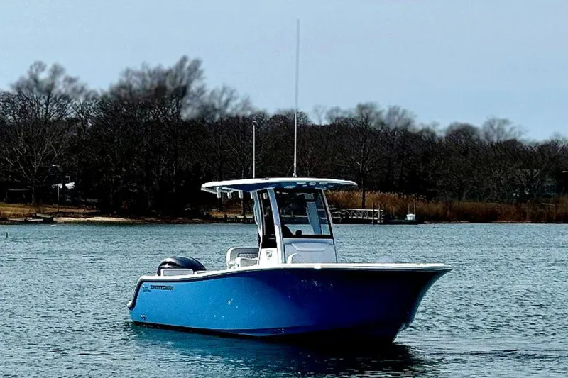Slide: The Image of 2024 Sportsman Heritage 231 Center Console boat cruising on a sunny lake. - 2