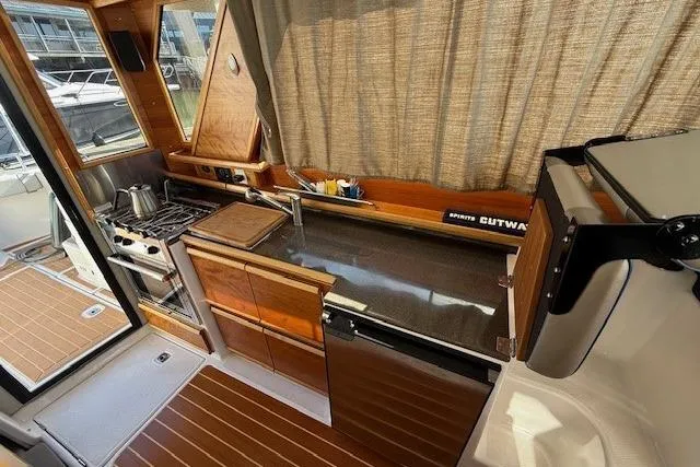 Slide: The Image of 2019 Cutwater 28 boat interior kitchen with stove, sink, and wooden cabinetry. - 13