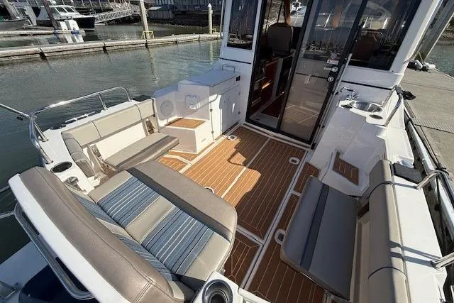 Slide: The Image of 2019 Cutwater 28 boat interior with seating, wood flooring, and dockside view. - 18