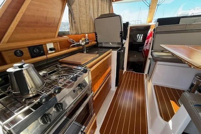 Slide: The Image of Interior of a 2019 Cutwater 28 boat featuring a compact kitchen and seating area. - 6