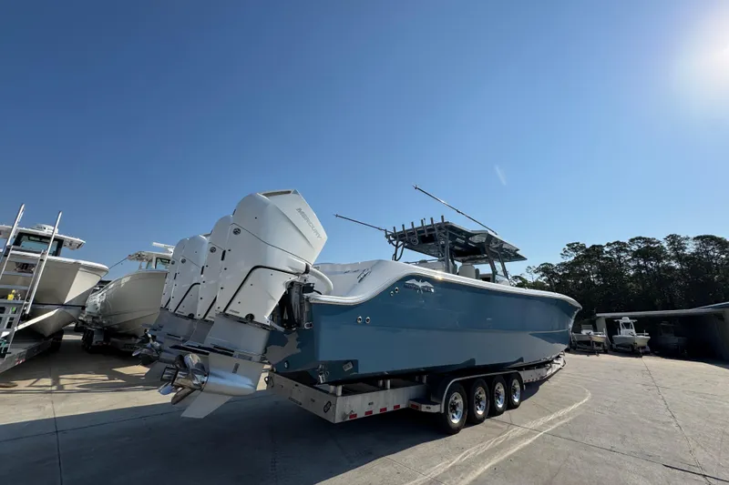 Slide: The Image of 2024 Invincible 46 Catamaran with triple outboard engines on a trailer, under clear blue sky. - 11