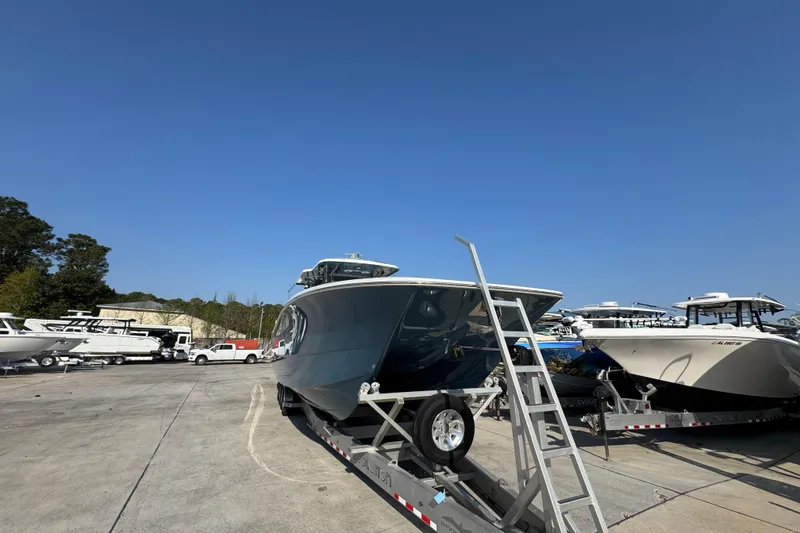 Slide: The Image of 2024 Invincible 46 Catamaran on trailer, parked outdoors under clear blue sky. - 5