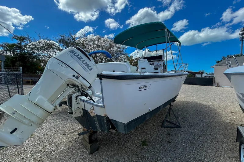 Slide: The Image of 1997 Boston Whaler 24 Outrage boat with Suzuki outboard motor, parked on gravel. - 4