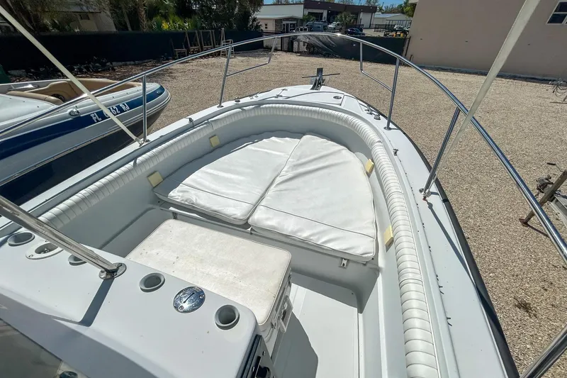 Slide: The Image of 1997 Boston Whaler 24 Outrage boat with cushioned seating and railings, parked on gravel. - 8