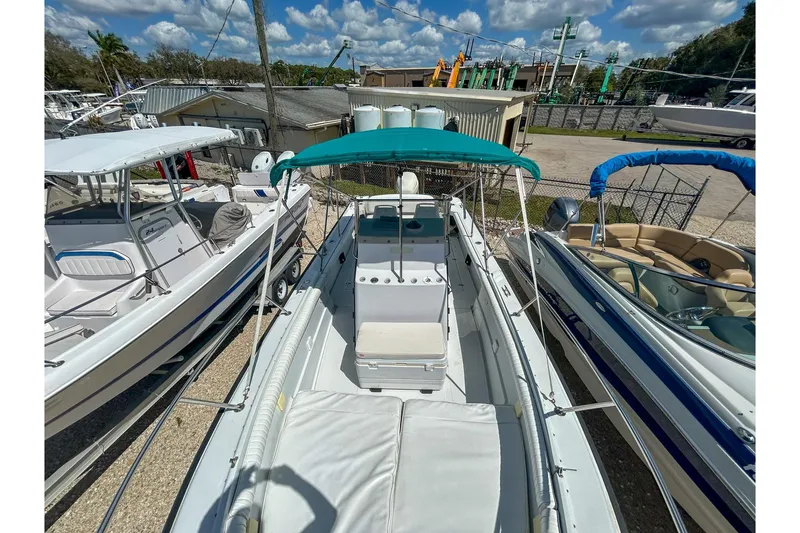 Slide: The Image of 1997 Boston Whaler 24 Outrage boat with teal canopy, docked under a sunny sky. - 9
