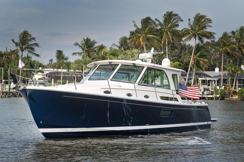 Slide: The Image of 2023 Back Cove 39O yacht cruising on a scenic waterway with palm trees. - 1