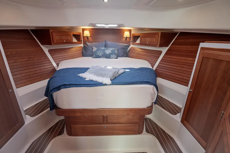 Slide: The Image of 2023 Back Cove 39O cabin interior with cozy bed, wooden accents, and ambient lighting. - 10
