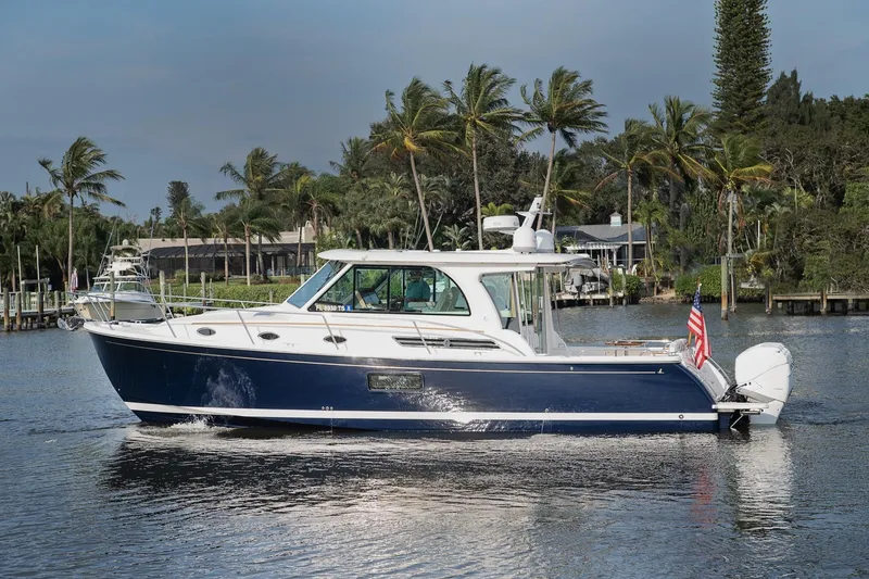 Slide: The Image of 2023 Back Cove 39O yacht cruising on a scenic waterway with palm trees. - 3