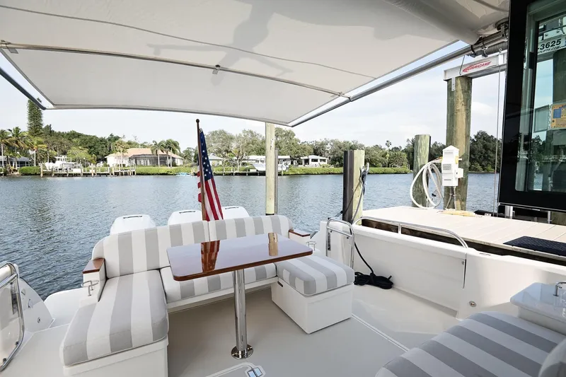 Slide: The Image of 2023 Back Cove 39O yacht with striped seating, table, and American flag by the water. - 38
