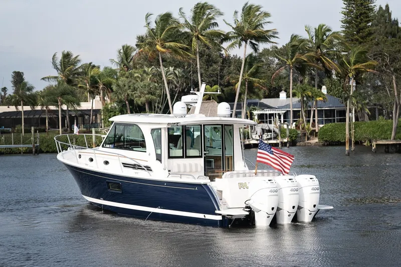 Slide: The Image of 2023 Back Cove 39O boat cruising on a scenic waterway with palm trees. - 4