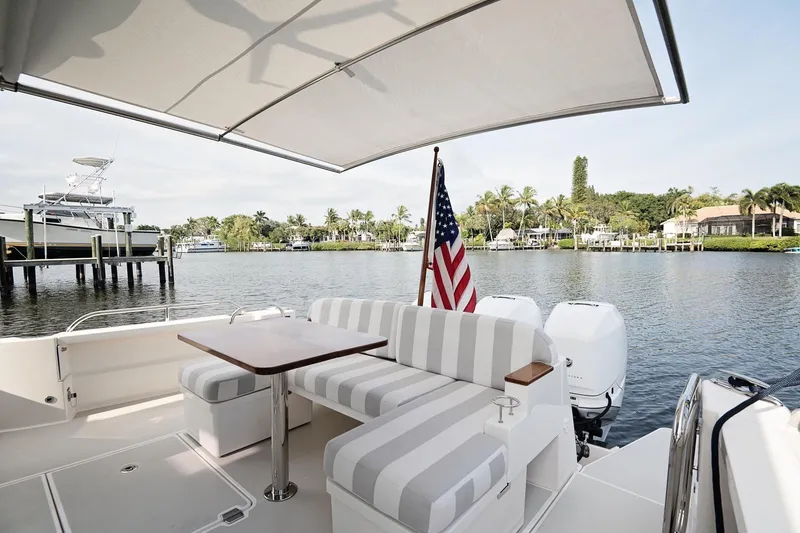 Slide: The Image of 2023 Back Cove 39O yacht with striped seating, table, and American flag on a serene waterway. - 40