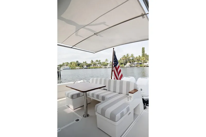 Slide: The Image of 2023 Back Cove 39O boat with striped seating and American flag, docked by a scenic waterfront. - 41