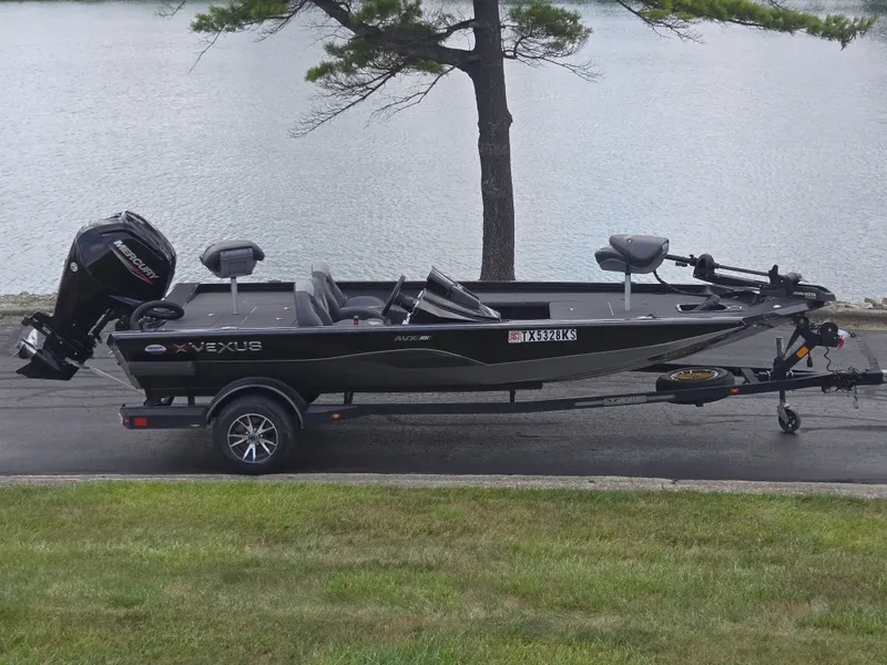 The Image of 2022 Vexus AVX181 boat on trailer by a lake, featuring a Mercury outboard motor. - 0