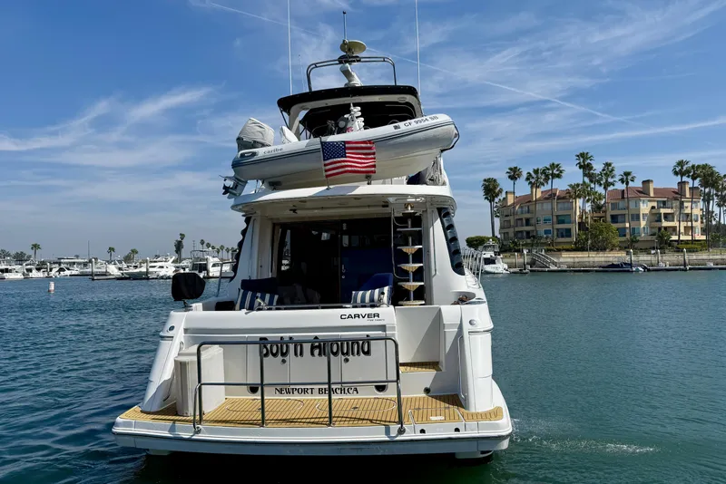 Slide: The Image of 2000 Carver 53 Voyager yacht docked in Newport Beach marina, featuring an American flag. - 100