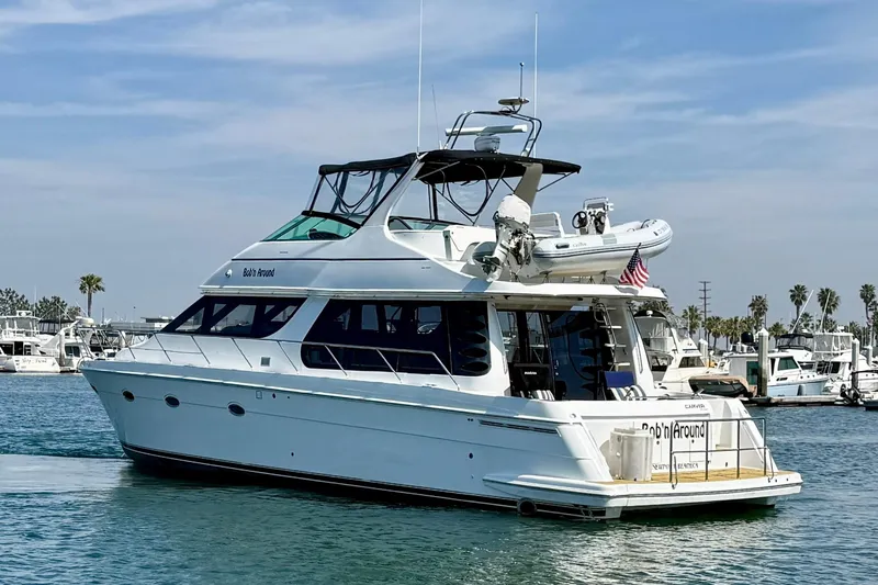 Slide: The Image of 2000 Carver 53 Voyager yacht docked in a marina, featuring sleek design and American flag. - 4