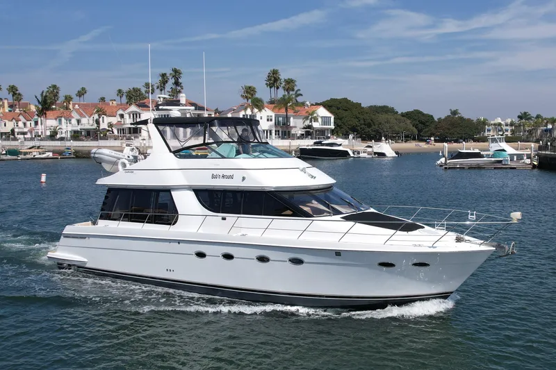 Slide: The Image of 2000 Carver 53 Voyager yacht cruising near a coastal residential area. - 5