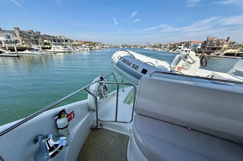 Slide: The Image of 2000 Carver 53 Voyager yacht on serene waterfront with luxury homes in background. - 74