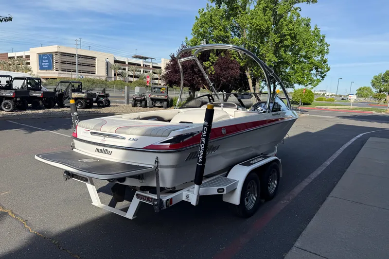 Slide: The Image of 2009 Malibu Response LXi boat on trailer in parking lot, surrounded by trees and vehicles. - 4