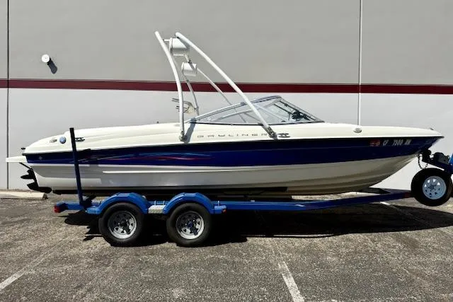 The Image of 2006 Bayliner 205 boat on trailer, white and blue design, parked outdoors. - 0