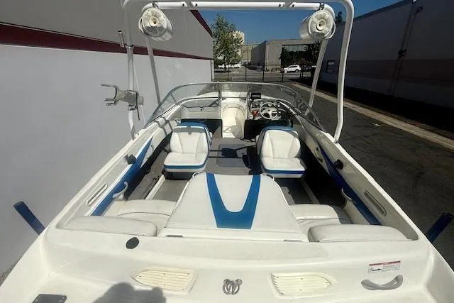 Slide: The Image of 2006 Bayliner 205 boat interior with white and blue seating, docked outdoors. - 11