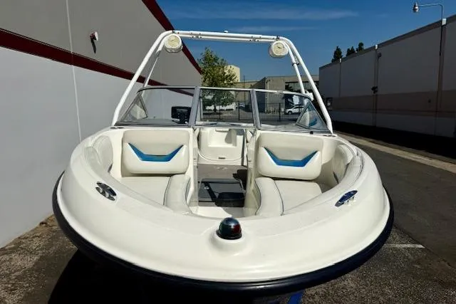 Slide: The Image of 2006 Bayliner 205 boat with white seating, parked outdoors near buildings. - 20