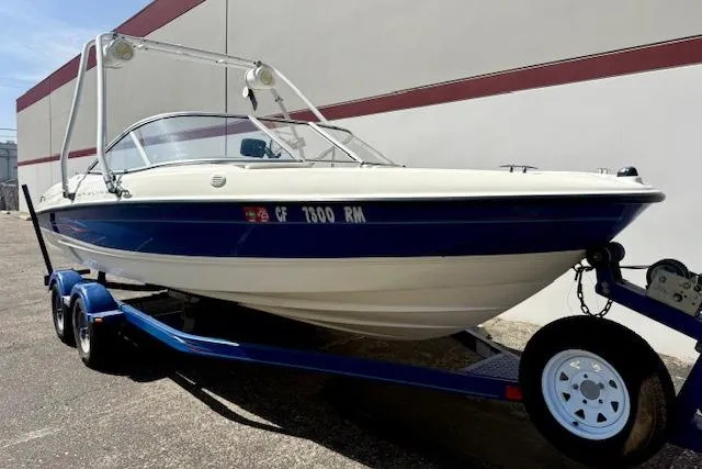 Slide: The Image of 2006 Bayliner 205 boat on trailer, blue and white, parked outdoors. - 4