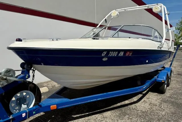 Slide: The Image of 2006 Bayliner 205 boat on trailer, blue and white exterior, parked outdoors. - 6