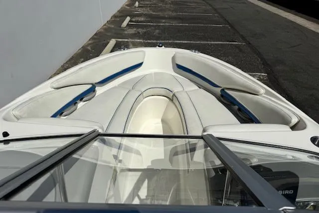 Slide: The Image of 2006 Bayliner 205 boat interior with white and blue seating, parked on asphalt. - 8