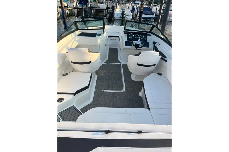 Slide: The Image of 2020 Sea Ray SPX 210 boat interior with white seating and modern dashboard at a marina. - 16