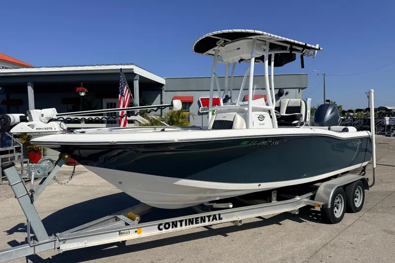 The Image of 2021 Tidewater 210 LXF boat on trailer, parked outdoors with American flag in background. - 1