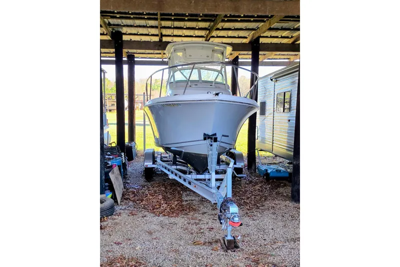 The Image of 2022 Sailfish 220 WAC boat on trailer under shelter, side view. - 0