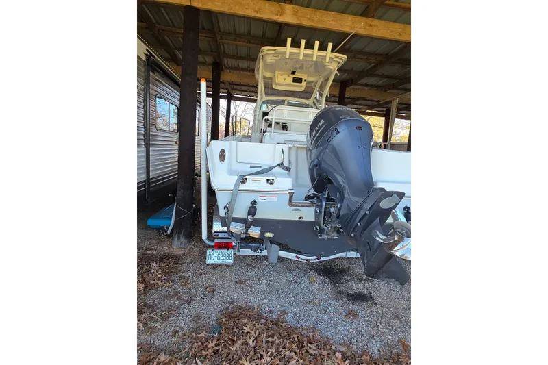 Slide: The Image of 2022 Sailfish 220 WAC boat interior with helm and seating under a covered dock. - 9