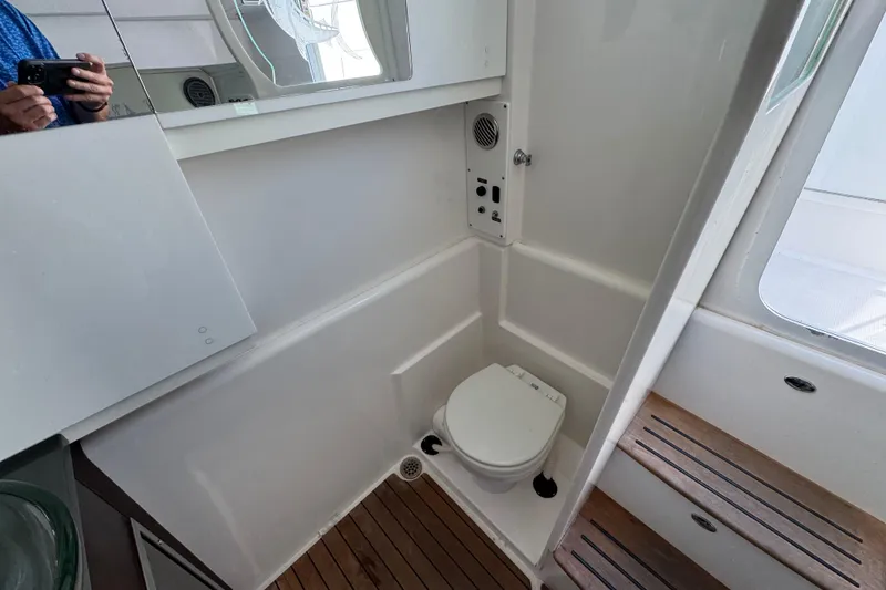 Slide: The Image of Interior of 2019 Everglades 435 Center Console boat bathroom with toilet and wooden flooring. - 26
