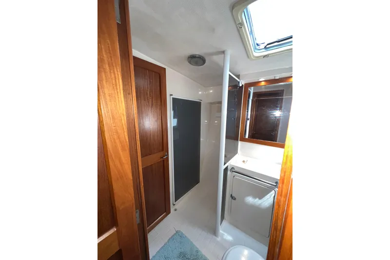 Slide: The Image of Interior of 1996 Riviera 4800 Sport Yacht bathroom with wooden accents and skylight. - 19