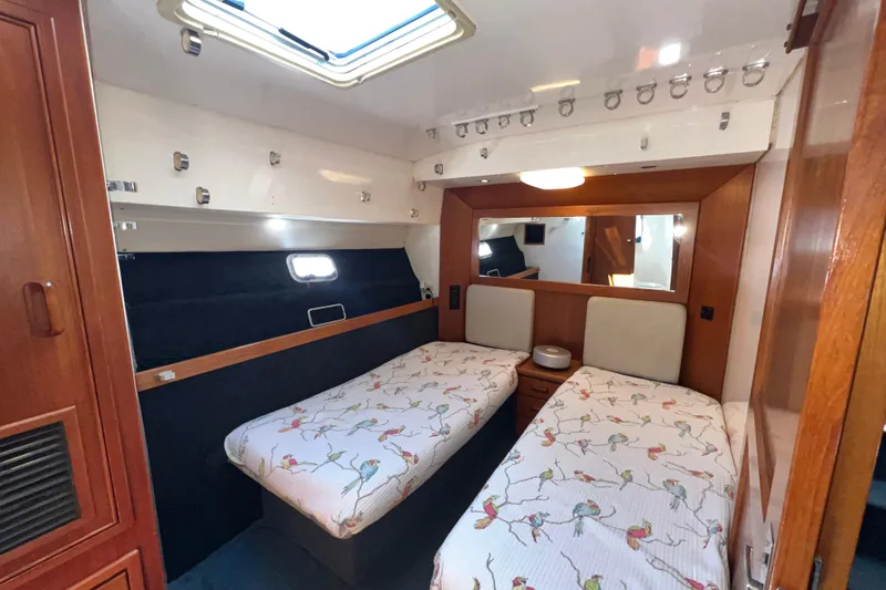 Slide: The Image of Interior of 1996 Riviera 4800 Sport Yacht with twin beds and wooden cabinetry. - 22