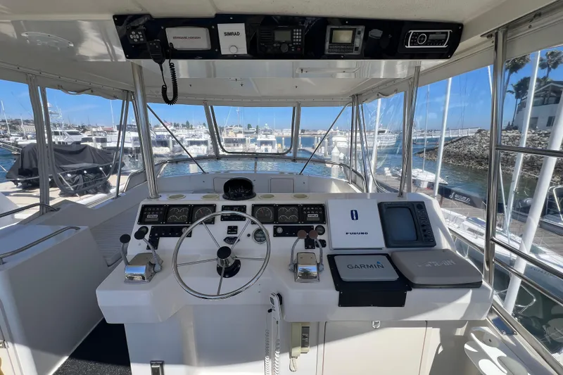 Slide: The Image of Cockpit of 1996 Riviera 4800 Sport Yacht with navigation equipment and marina view. - 33
