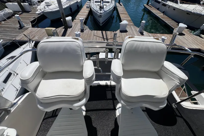 Slide: The Image of Two white captain's chairs on a 1996 Riviera 4800 Sport Yacht at a marina. - 40