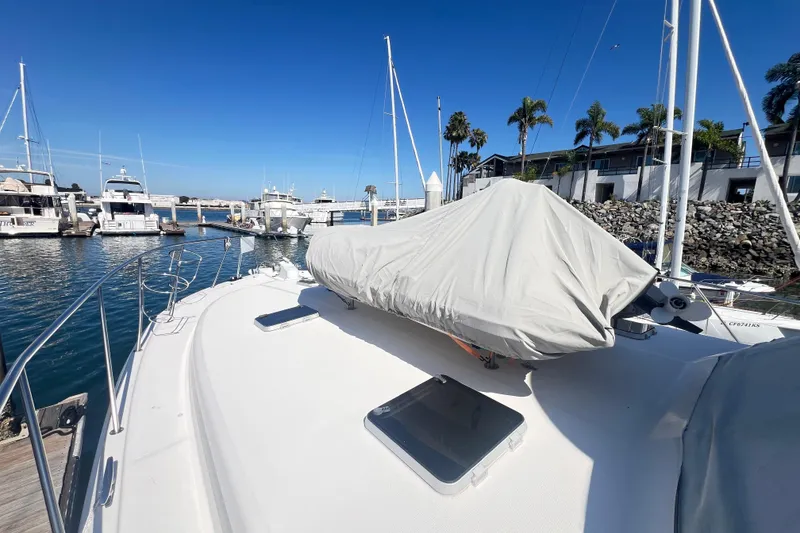 Slide: The Image of 1996 Riviera 4800 Sport Yacht docked at marina, covered deck, clear blue sky. - 93