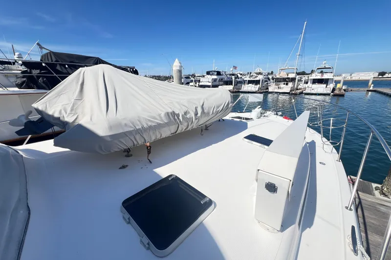 Slide: The Image of 1996 Riviera 4800 Sport Yacht docked at marina, covered equipment on deck, clear blue sky. - 95