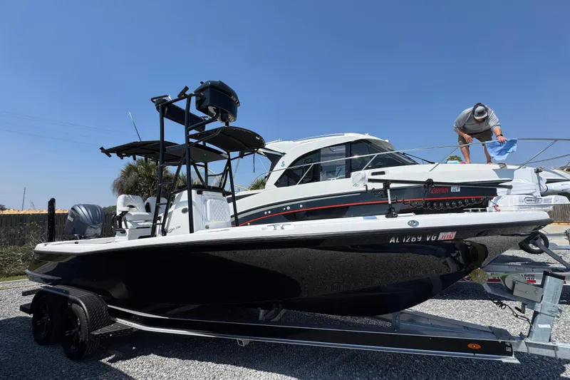 Slide: The Image of 2025 BlackJack 256 Coastal boat on trailer, person cleaning, clear blue sky. - 1
